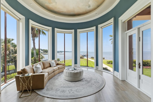 interior space with a water view, ornamental molding, wood finished floors, and plenty of natural light
