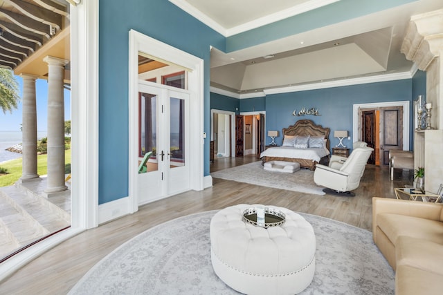 bedroom featuring multiple windows, decorative columns, hardwood / wood-style flooring, and french doors