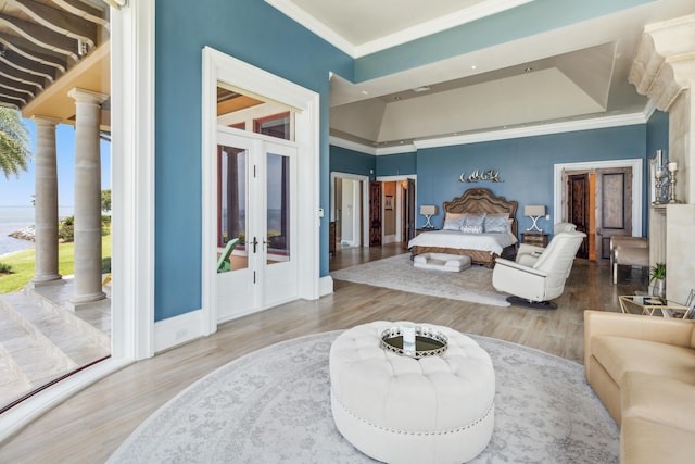 bedroom featuring crown molding, french doors, decorative columns, and wood finished floors