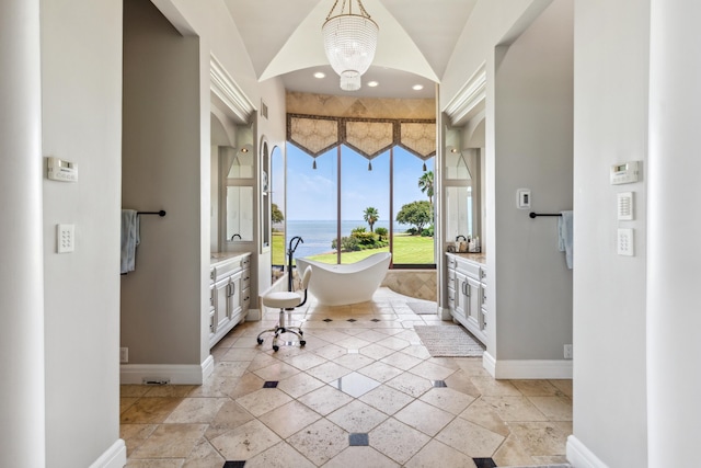 entrance foyer featuring light tile patterned floors, a notable chandelier, and a water view