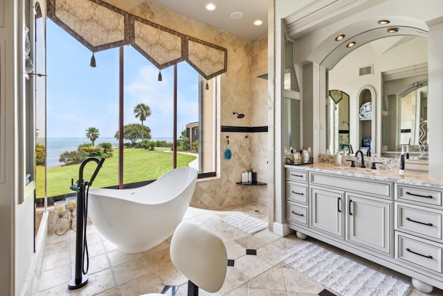 bathroom with a tub, tile patterned floors, a water view, vanity, and tile walls