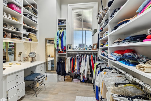 spacious closet with light wood-type flooring and built in desk