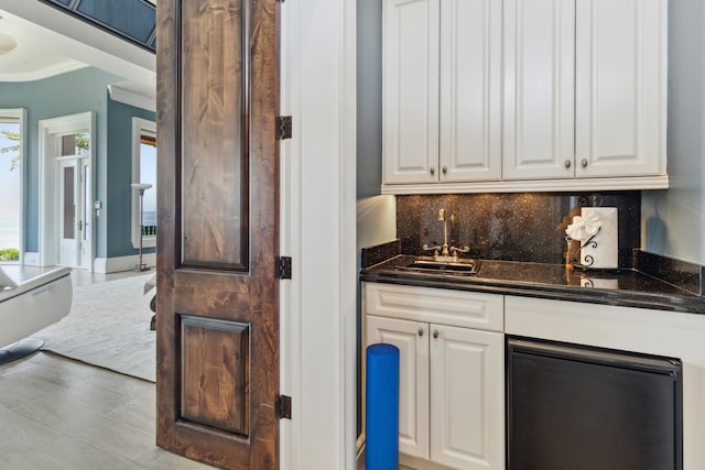 bar featuring decorative backsplash, indoor wet bar, a sink, and crown molding