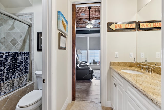 bathroom featuring a tile shower, toilet, vanity, a ceiling fan, and tile patterned flooring