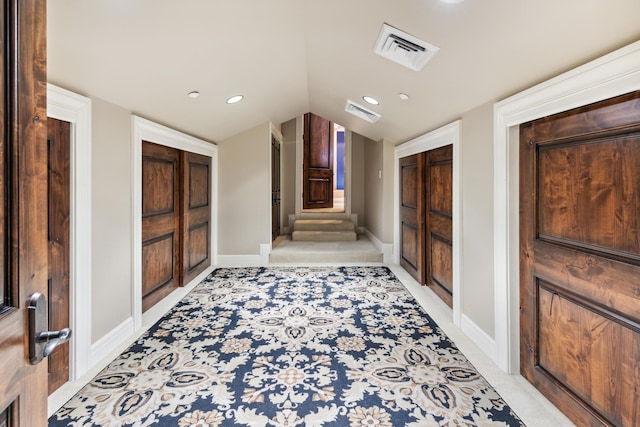 hall featuring light colored carpet and lofted ceiling