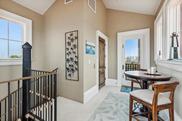 hall with vaulted ceiling and light colored carpet