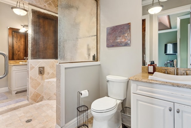 full bath featuring vanity, a tile shower, toilet, ornamental molding, and baseboards