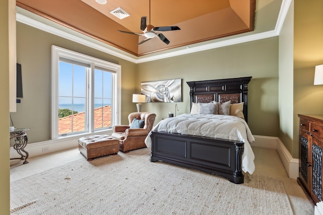 carpeted bedroom with ceiling fan, a tray ceiling, and ornamental molding