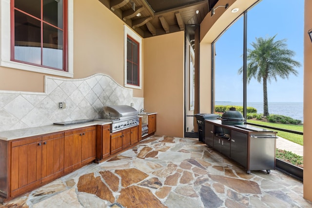 sunroom featuring beamed ceiling and a water view