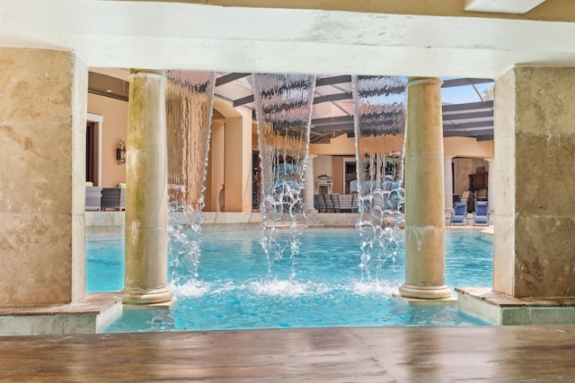 view of swimming pool featuring pool water feature and decorative columns