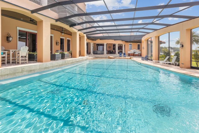 view of pool with ceiling fan, glass enclosure, and a patio