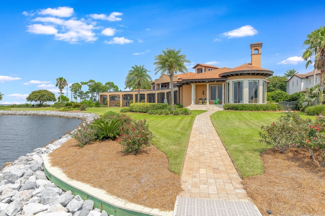 rear view of house featuring a yard and a water view