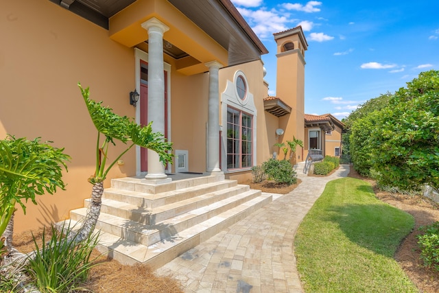 entrance to property featuring a patio and a lawn