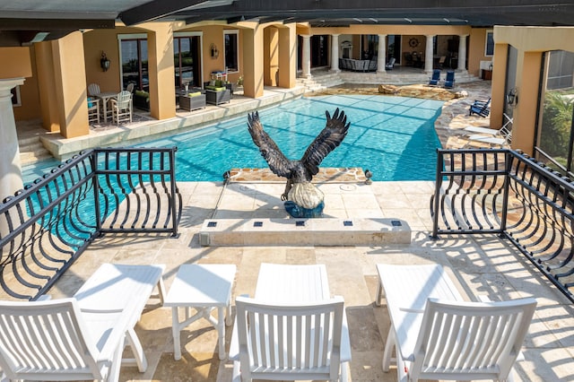 community pool with an outdoor living space and a patio area