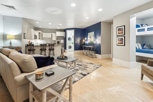 tiled living room with stacked washer and dryer and sink