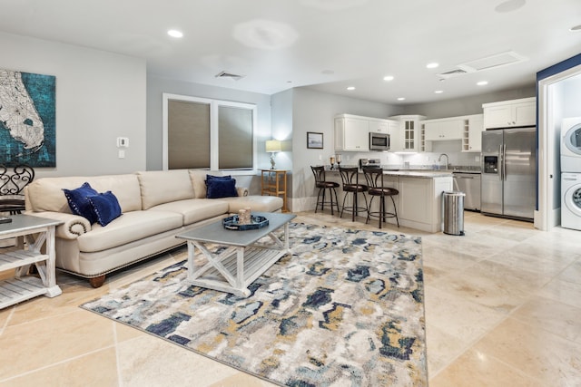 living area with stacked washer and dryer, visible vents, and recessed lighting