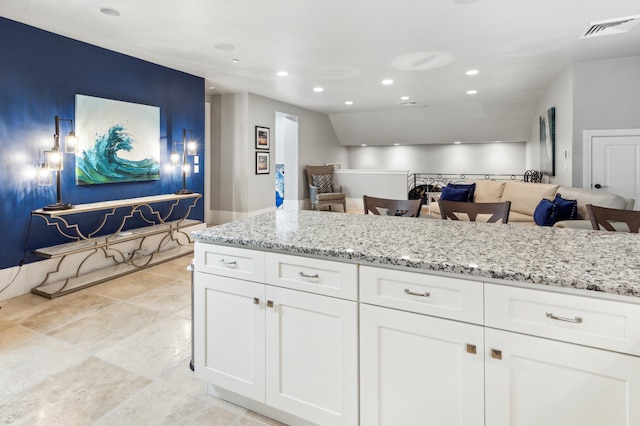 kitchen featuring white cabinets, light stone countertops, and light tile patterned floors