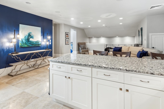 kitchen with light stone countertops, recessed lighting, and white cabinets