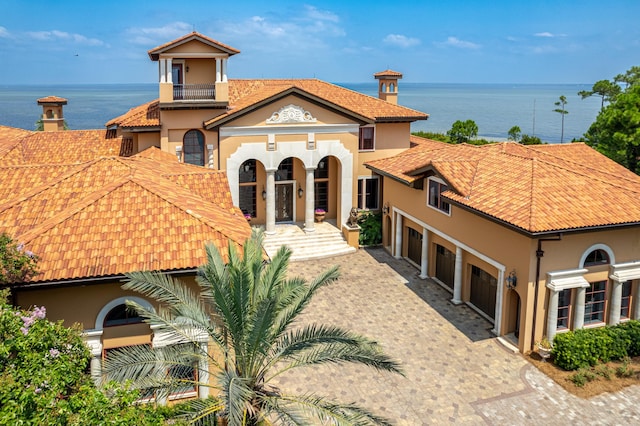 mediterranean / spanish home with stucco siding, a water view, a garage, and decorative driveway