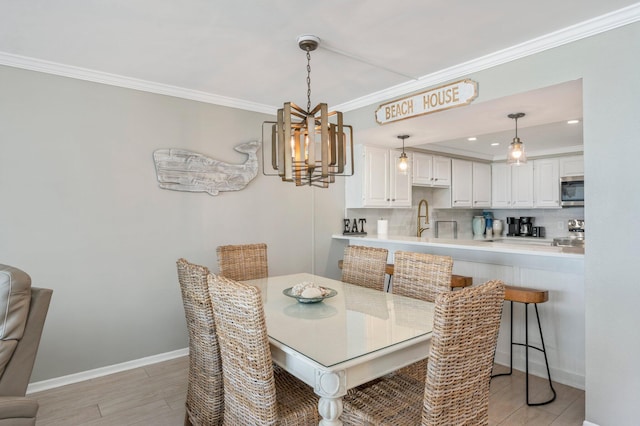 dining area featuring crown molding, light wood finished floors, and baseboards