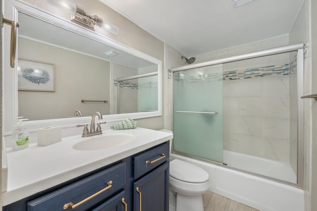 full bath featuring toilet, combined bath / shower with glass door, wood finished floors, and vanity