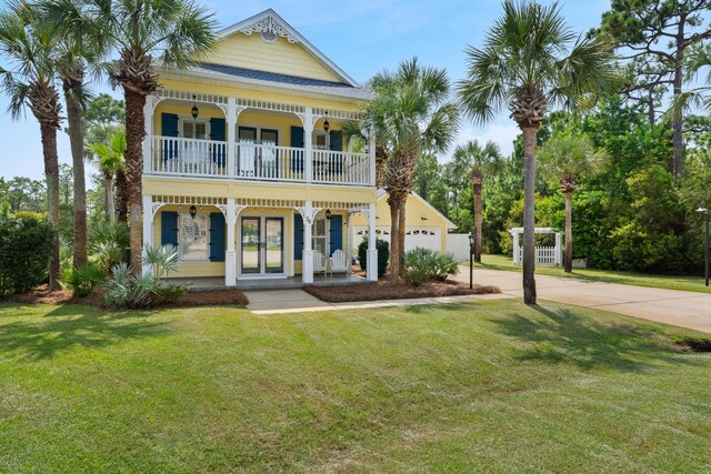 view of front facade with a front lawn, covered porch, french doors, and a garage