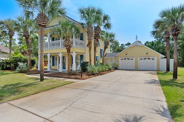 view of front facade featuring a garage, covered porch, a balcony, a front yard, and an outdoor structure