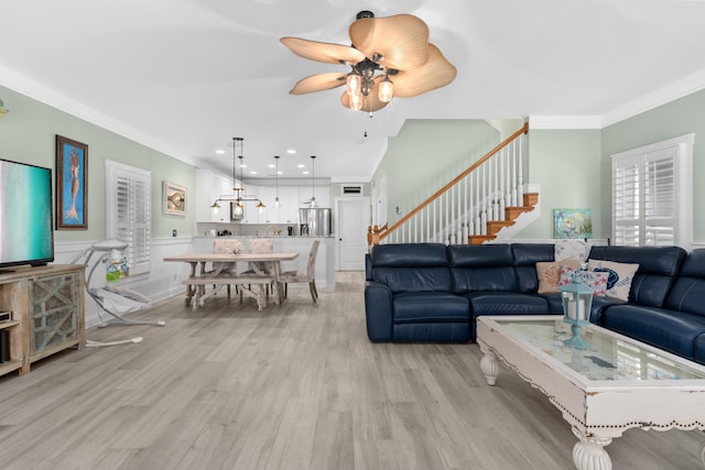 living room with light wood-type flooring, crown molding, and ceiling fan