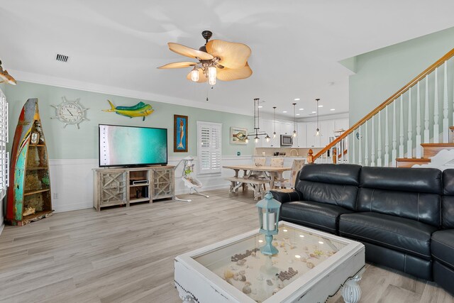 living room featuring ceiling fan, ornamental molding, and light hardwood / wood-style floors