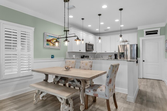 dining space with light hardwood / wood-style flooring and ornamental molding