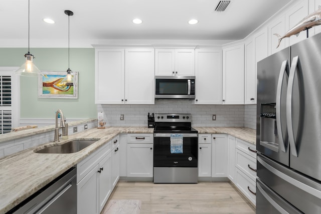 kitchen with white cabinetry, stainless steel appliances, sink, and pendant lighting