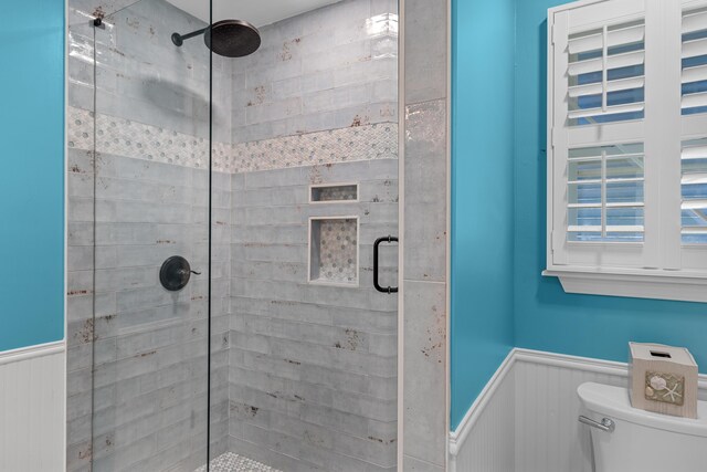 bathroom featuring toilet and a shower with shower door