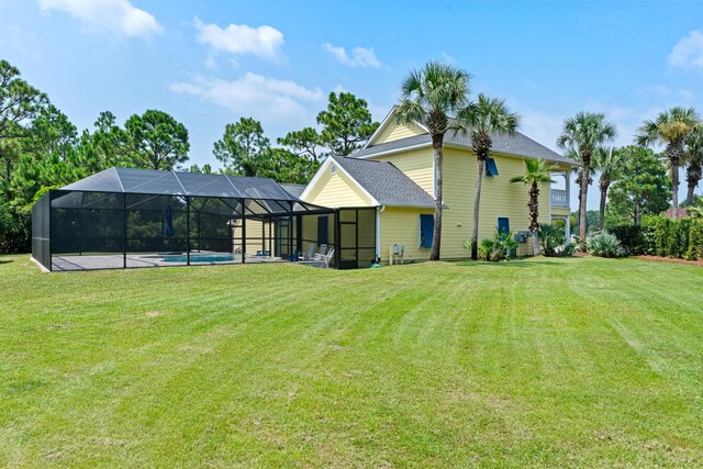 rear view of house with a lawn, glass enclosure, and a patio