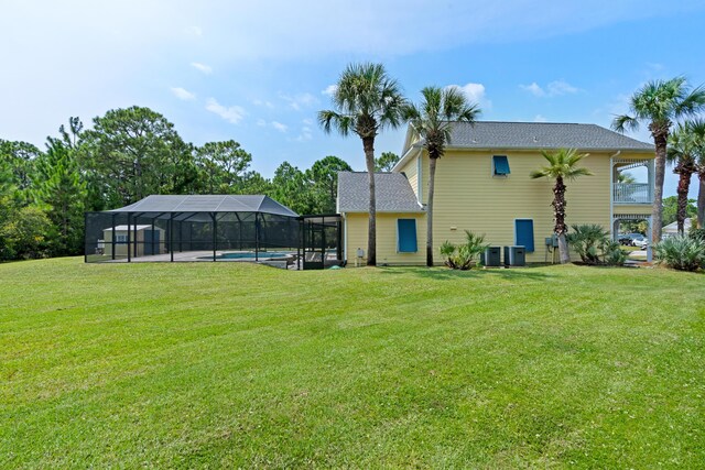 back of house with a lanai, central AC unit, and a yard