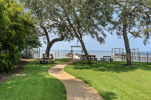 view of property's community featuring a water view, a yard, and a dock