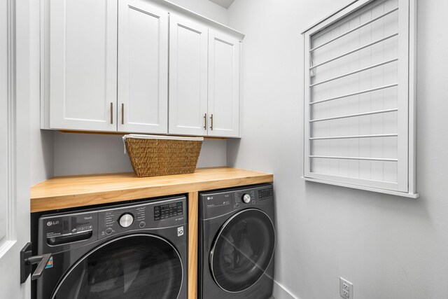 clothes washing area featuring cabinets and washer and clothes dryer