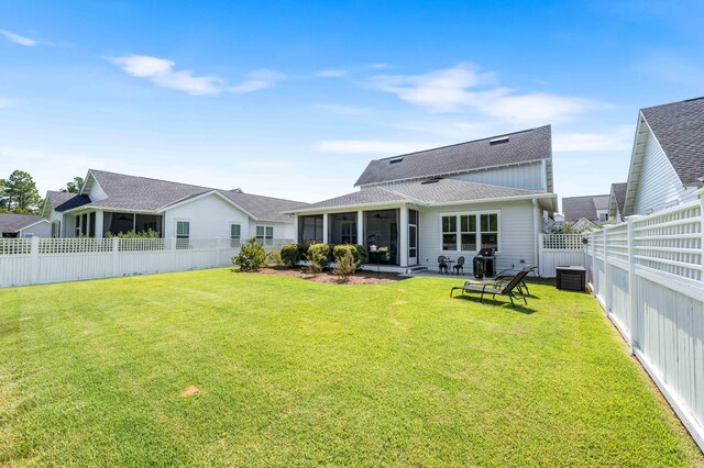 rear view of house with a sunroom, central AC unit, and a yard