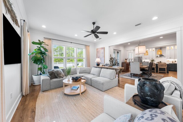 living room featuring crown molding, ceiling fan, and hardwood / wood-style flooring