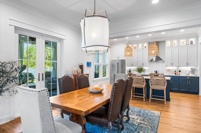 dining area featuring light hardwood / wood-style floors, ornamental molding, and french doors