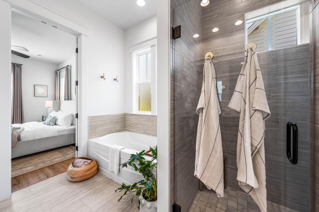 bathroom featuring shower with separate bathtub, hardwood / wood-style floors, and ceiling fan