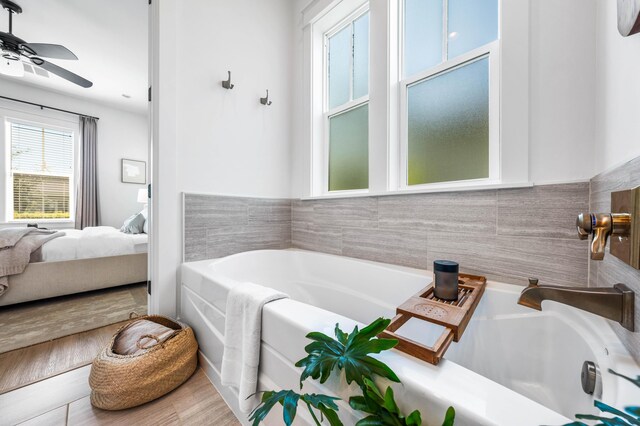 bathroom with a bathing tub, ceiling fan, and hardwood / wood-style flooring