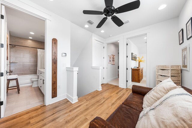 bedroom featuring ceiling fan, ensuite bath, and light hardwood / wood-style floors