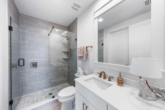 bathroom with hardwood / wood-style flooring, vanity, toilet, and an enclosed shower