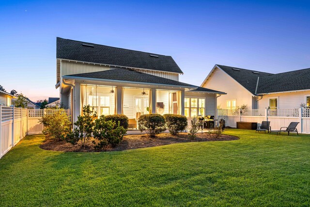 back house at dusk with a lawn, a patio, and ceiling fan