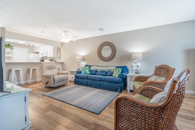 living room with ceiling fan and light hardwood / wood-style flooring