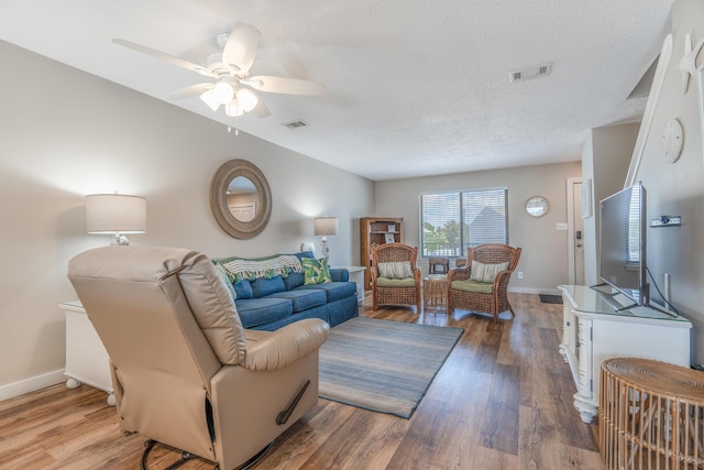 living room with hardwood / wood-style flooring, ceiling fan, and a textured ceiling