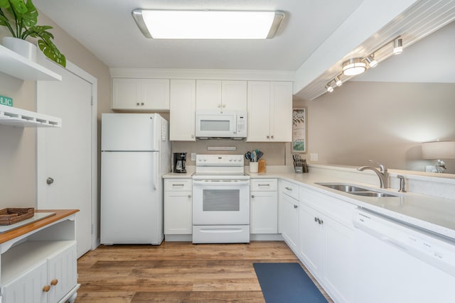 kitchen with sink, white appliances, light hardwood / wood-style floors, white cabinets, and kitchen peninsula