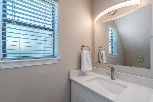 bathroom with vanity and lofted ceiling