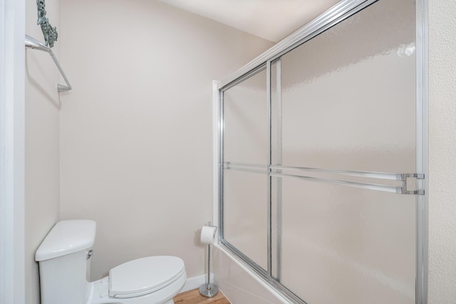 bathroom with bath / shower combo with glass door and toilet