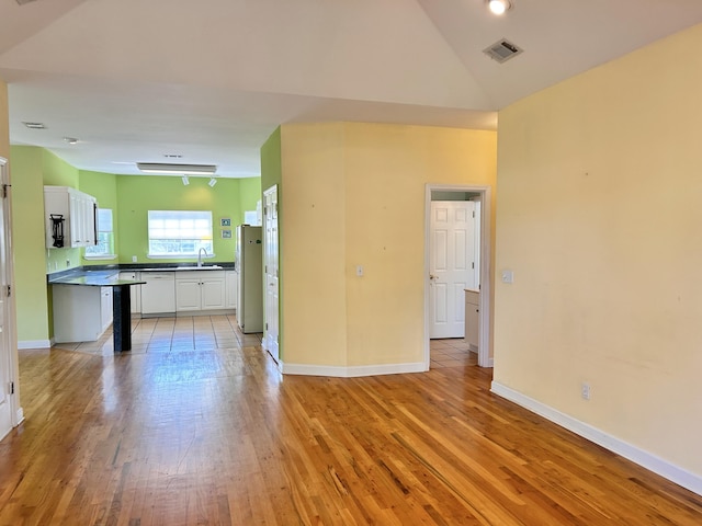 interior space featuring high vaulted ceiling, sink, and light hardwood / wood-style flooring